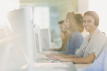 Portrait lächelnde Geschäftsfrau mit Headset bei der Arbeit am Computer im Büro - HOXF01020