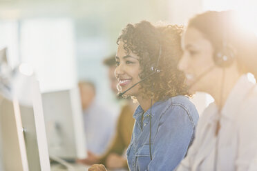 Businesswomen with headsets working at computers in office - HOXF01022