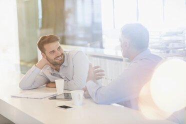 Businessmen with digital tablet and coffee talking in office - HOXF01024