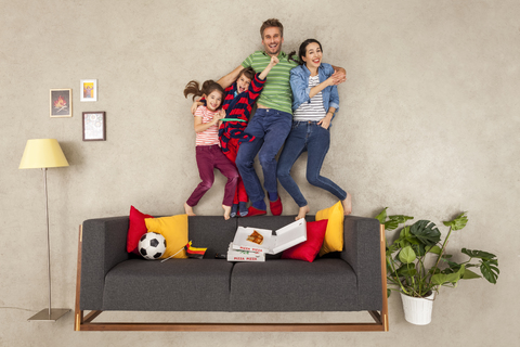 Glückliche Familie mit zwei Kindern beim Fußballschauen im Wohnzimmer, lizenzfreies Stockfoto
