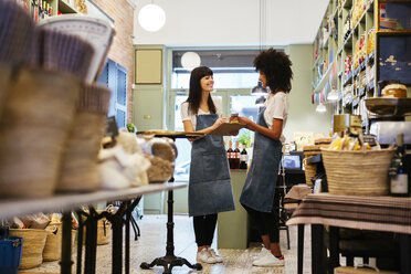 Two smiling women standing in a store with clipboard - EBSF02201