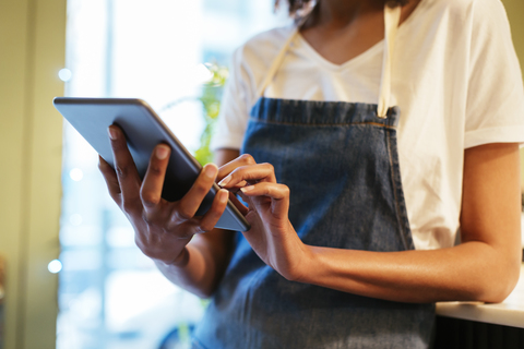 Nahaufnahme einer Frau, die in einem Geschäft ein Tablet benutzt, lizenzfreies Stockfoto