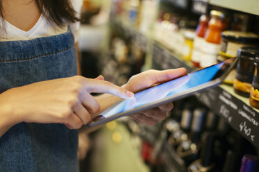 Close-up of woman using tablet at shelf in a store - EBSF02222