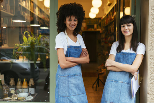 Porträt von zwei lächelnden Frauen, die in der Eingangstür eines Geschäfts stehen - EBSF02231