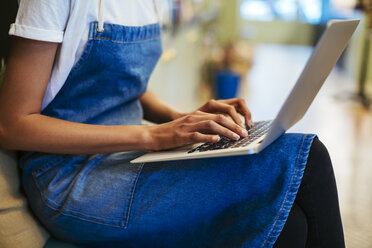 Close-up of woman using laptop in a store - EBSF02251