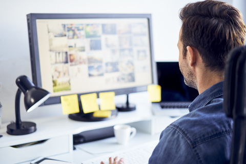 Bildredakteurin bei der Arbeit am Computer am Schreibtisch im Büro, lizenzfreies Stockfoto