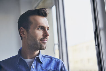 Porträt eines selbstbewussten Mannes, der aus dem Fenster schaut - BSZF00245