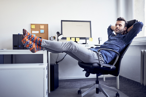 Man sitting at desk in office having a power nap stock photo