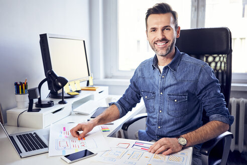 Porträt eines lächelnden Web-Designers, der an einem Entwurf am Schreibtisch im Büro arbeitet - BSZF00263