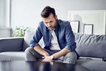 Besorgter, trauriger Mann sitzt auf dem Sofa - BSZF00290