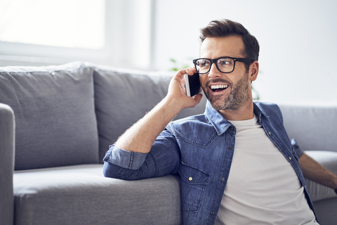 Happy man in living room talking on cell phone stock photo