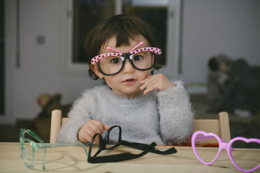 Porträt eines kleinen Mädchens, das mit einer Spielzeugbrille spielt - GEMF01898
