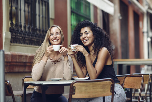 Zwei glückliche Freunde trinken Kaffee in einem Straßencafé - JSMF00050