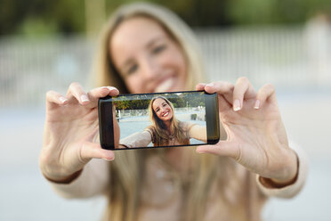 Glückliche junge Frau, die ein Selfie mit ihrem Mobiltelefon macht, Nahaufnahme - JSMF00055