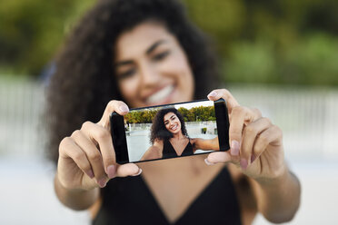 Glückliche junge Frau, die ein Selfie mit ihrem Mobiltelefon macht, Nahaufnahme - JSMF00056