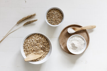 Rye ears and bowls of rye flakes, rye flour and rye grains on white background - EVGF03291