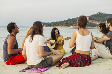 Thailand, Koh Phangan, group of people sitting on a beach with guitar - MOMF00385