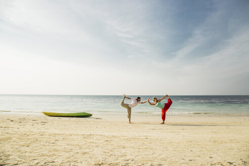 Thailand, Koh Phangan, couple doing yoga on a beach - MOMF00388