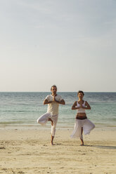 Thailand, Koh Phangan, couple doing yoga on a beach - MOMF00389