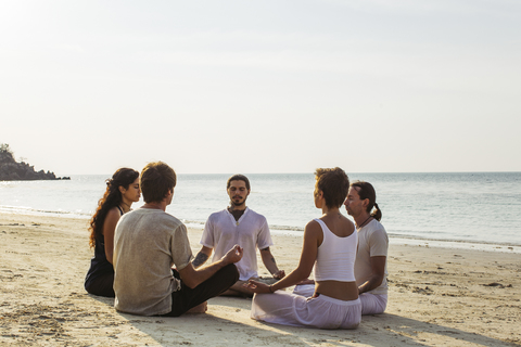 Thailand, Koh Phangan, Gruppe von Menschen, die gemeinsam am Strand meditieren, lizenzfreies Stockfoto