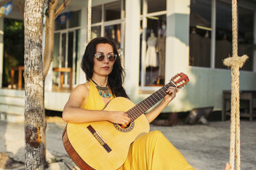 Thailand, Koh Phangan, Frau spielt Gitarre am Strand - MOMF00401