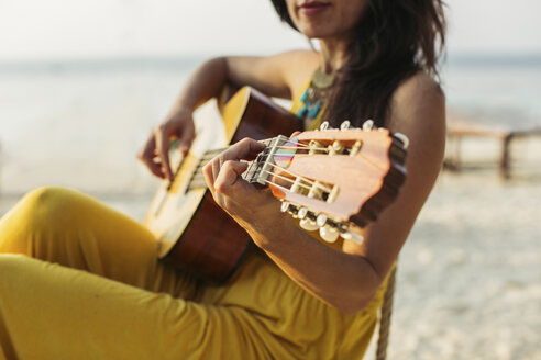 Thailand, Koh Phangan, Frau spielt Gitarre am Strand - MOMF00403