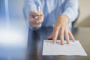 Person sitting at office desk presenting ballpen and contract - ZEF15105