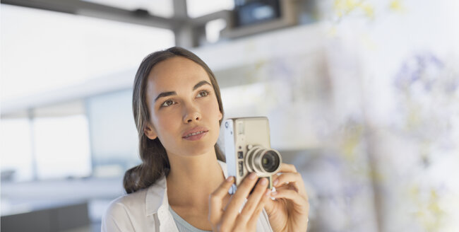 Ernste brünette Frau mit Digitalkamera - HOXF01028