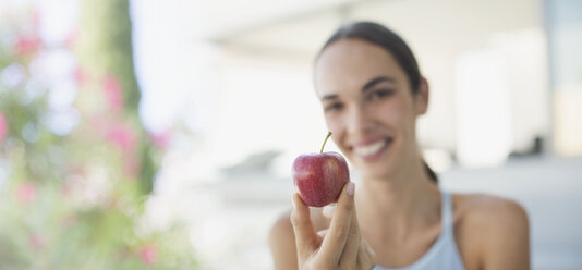 Portrait smiling brunette woman holding red apple - HOXF01048
