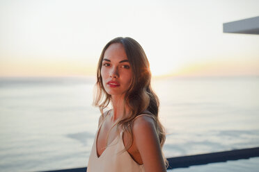 Portrait serious, beautiful woman on luxury patio with sunset ocean view - HOXF01061