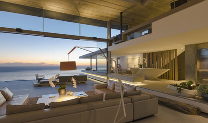 Beleuchtetes modernes Luxus-Wohnzimmer mit Meerblick in der Abenddämmerung - HOXF01068