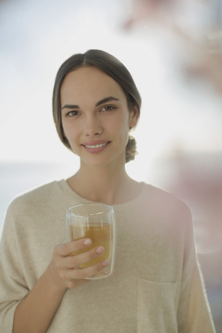 Porträt lächelnde brünette Frau trinkt Saft, lizenzfreies Stockfoto