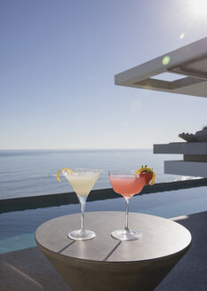 Cocktails in Martinigläsern auf der sonnigen Luxusterrasse mit Meerblick - HOXF01078