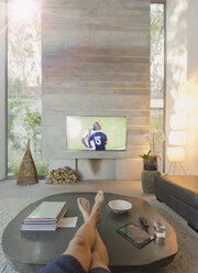 Personal perspective man watching soccer on TV in living room - HOXF01093