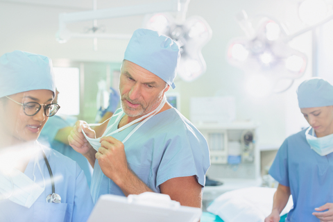 Chirurgen mit Klemmbrett besprechen den Papierkram im Operationssaal, lizenzfreies Stockfoto