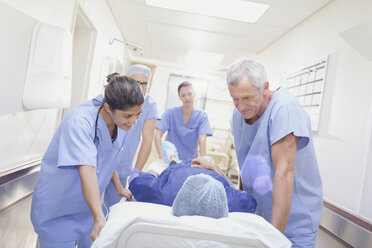 Pflegende Chirurgen schieben einen Patienten auf einer Bahre durch den Krankenhausflur - HOXF01115