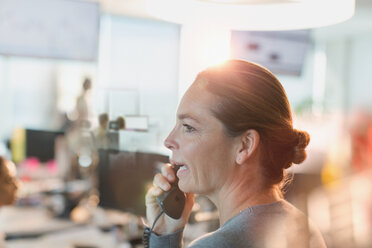 Profile businesswoman talking on telephone in office - HOXF01165