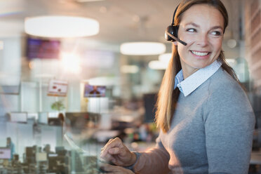 Lächelnde Geschäftsfrau mit Headset bei der Arbeit im Büro - HOXF01178