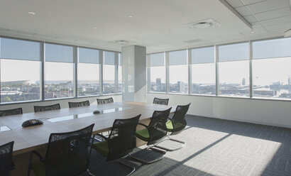 Stühle und Konferenztisch in einem sonnigen städtischen Konferenzraum - HOXF01187