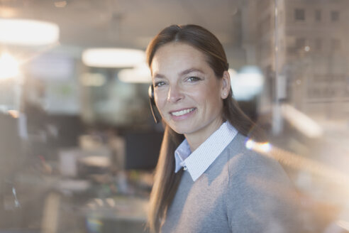 Porträt einer lächelnden, selbstbewussten Geschäftsfrau mit Headset im Büro - HOXF01189