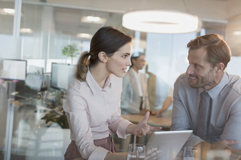 Businesswoman with digital tablet explaining to businessman in office meeting - HOXF01199