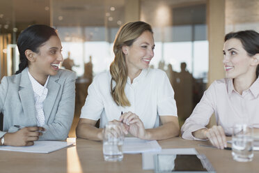 Lächelnde Geschäftsfrauen unterhalten sich in einem Konferenzraum - HOXF01215