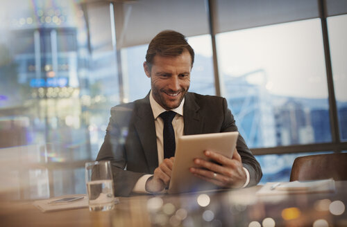 Lächelnder Geschäftsmann mit digitalem Tablet im Konferenzraum - HOXF01237