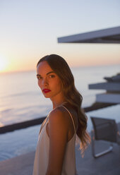 Portrait serious, beautiful woman on sunset patio with ocean view - HOXF01273