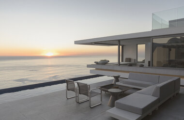 Blick auf den Sonnenuntergang über dem Meereshorizont von der modernen, luxuriösen Musterhaus-Außenterrasse - HOXF01291
