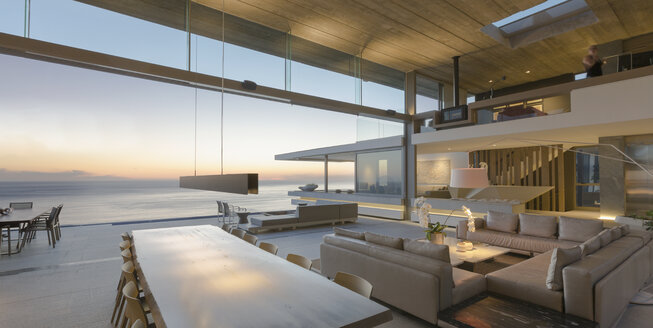 Modernes, luxuriöses Haus mit Wohnzimmer und Esszimmer mit Blick auf das Meer in der Abenddämmerung - HOXF01302