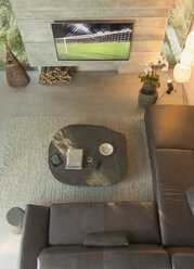 View from above soccer game on TV in modern, luxury home showcase interior living room - HOXF01327