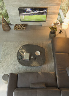 Blick von oben auf ein Fußballspiel im Fernsehen in einem modernen, luxuriösen Wohnzimmer mit Vitrine - HOXF01327