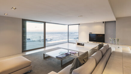 Modern, minimalist luxury living room with patio doors open to ocean view - HOXF01347