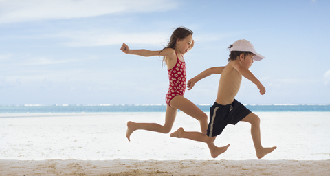 Junge und Mädchen Bruder und Schwester laufen am tropischen Strand, lizenzfreies Stockfoto